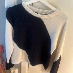 Svartvit stickad tröja Gina Tricot - Snygg stickad tröja från Gina Tricot i svart och vitt med coolt, abstrakt mönster. Tröjan har rund halsringning och långa ärmar. Perfekt för dig som gillar en chill och trendig stil.