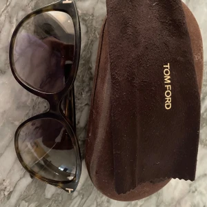 Tom Ford solglasögon brunmelerad - Snygga solglasögon från Tom Ford med brunmelerad båge och stora, rundade glas. Kommer med originalfodral och putsduk. Fodralet slutet, troligen för legat i handväska. 