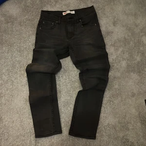 Levi's 512 Slim Taper svarta jeans - Svarta Levi's 512 Slim Taper jeans med klassisk femficksdesign och snyggt smal passform som smalnar av vid ankeln. Jeansen har en stilren look och är tillverkade i stretchigt denim för extra komfort. Perfekta för dig som gillar en modern och clean stil.