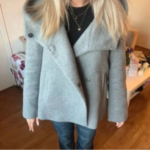 Zara kappa - Snygg grå kappa från Zara med stor, bred krage och dubbelknäppning framtill. Jackan har raka ärmar samt två fickor på sidorna. Perfekt för dig som gillar stilren och modern look. Hör av dig vid frågor💗