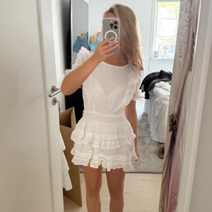 Vit volangklänning med puffärm - Supersöt vit kortklänning till sommarn från Gina Tricot 9-14. Klänningen har smock i midjan, rund halsringning och fina volangdetaljer både fram och bak. Str 146-152