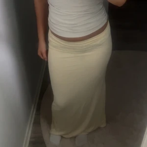 Ljusgul långkjol i stretchigt tyg - Supersnygg ljusgul långkjol med tight passform och hög midja. Kjolen är enkel och stilren utan mönster, perfekt att styla med crop tops eller stickade tröjor. Mjuk och följsam känsla, passar både till sneakers och sandaler.