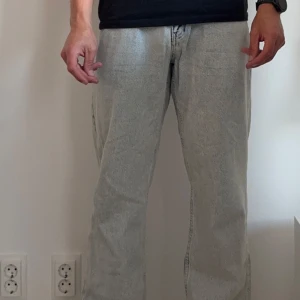 Ljusblåa wide jeans från Woodbird - Säljer ett par ljusgråa jeans från Woodbird med relaxed fit och breda ben. Jeansen har klassisk femficksdesign, läderpatch bak och är tillverkade i bomull. Perfekta för dig som gillar en loose och avslappnad stil.