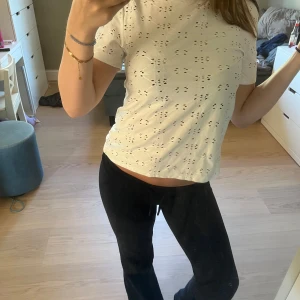Vit kortärmad blus med broderi - Superfin vit blus med korta ärmar och broderade hålmönster över hela tyget. Toppen har en rak, lite croppad passform och är gjord i mjuk bomull. Perfekt för en fräsch och somrig look!