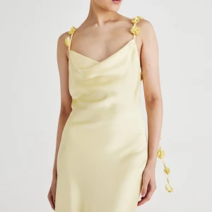 Ljusgul långklänning med blommiga axelband - Superfin ljusgul långklänning i satinliknande material med smala axelband dekorerade med små blommor.🌼 Klänningen har en draperad urringning och en relativt öppen rygg! Den går ned i marken på mig som är 170!💕Den är aldrig använd och har prislappen kvar, säljer den då jag tyvärr behöver pengarna