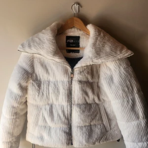 Vit teddyjacka från Sisters Point - Supermjuk och fluffig vit teddyjacka från Sisters Point med bred krage och dragkedja framtill. Jackan har quiltad look och är perfekt för dig som vill ha en mysig och trendig stil. Passformen är normal och jackan har långa ärmar.