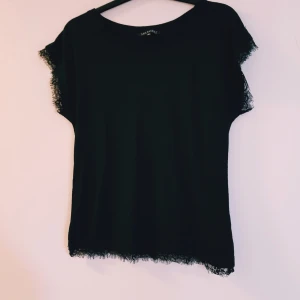 Svart topp med spets från Top Secret strl 38 - Svart topp från Top Secret med korta ärmar och snygga spetsdetaljer längs ärmslut och nederkant. Enkel och stilren design som passar perfekt till jeans eller kjol. Tunn och mjuk känsla, rund halsringning och rak passform.  Helt skick dock noppror