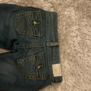 True Religion jeans - Hej säljer ett par jätte snygga true religon jeans för dem är för stora! Jätte bra skick det är bara lite upspröttande längst ner på grand av trampning men inte mycket, skriv om ni vill ha bild. Det står att det är strl w26 men dom är lite mindre för det är gammal model men borde ändå passa.