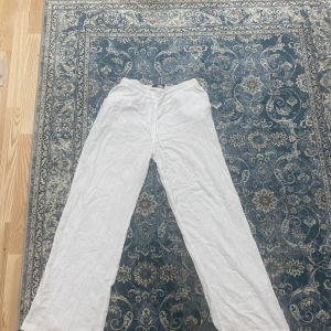 Vita linnebyxor från Gina Tricot - Luftiga vita linnebyxor från Gina Tricot i storlek S. Byxorna har rak passform, elastisk midja med snörning och är perfekta för varma dagar. Snyggt avslappnad stil och superbekväma att bära.