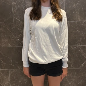 Vit långärmad tröja från Zara - Enkel och stilren vit långärmad tröja från Zara i storlek S. Tröjan har rund halsringning och är gjord i ett mjukt material som känns skönt mot huden. Passformen är normal och den är perfekt för lager-på-lager under höst och vår.