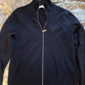 Marinblå stickad kofta Selected Homme - Snygg marinblå stickad kofta från Selected Homme med hel dragkedja framtill och ribbad krage. Perfekt för lager-på-lager och passar till både jeans och chinos. Klassisk och stilren design som funkar året runt. Den är nästan ny använd cirka 2 gånger, nypris 800 kr