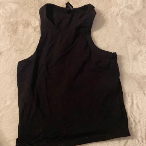 Svart linnetopp från Boohoo - En stilren svart linnetopp från Boohoo med klassisk rak passform och breda axelband. Toppen är ärmlös och har en enkel, clean look som funkar till allt. Perfekt att matcha med jeans eller kjol för en chill vibe.