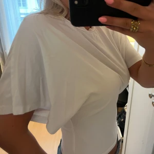 Vit croppad t-shirt med loose fit - Säljer en vit croppad t-shirt med loose fit och korta ärmar. T-shirten har en enkel och clean look med rund halsringning och är tillverkad i mjukt bomullstyg. Perfekt för en chill och avslappnad stil.