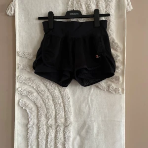 Svarta träningsshorts från Champion - Svarta träningsshorts från Champion i meshmaterial med sportig look. De har elastisk midja och klassisk Champion-logga på ena benet. Perfekta för gymmet eller löprundan, riktigt sköna och lätta på kroppen.