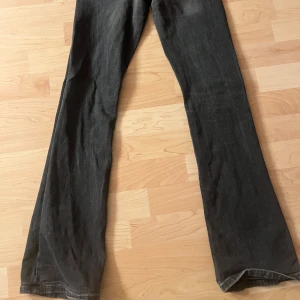 Svarta bootcut jeans från Gina Tricot - Snygga svarta jeans från Gina Tricot i bootcut-modell. Jeansen har coola fickor med lock och knapp både fram och bak, samt klassisk dragkedja. Materialet är jeans med en mörk tvätt och detaljerade sömmar. Perfekta för dig som gillar en retro vibe.