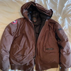 Brun dunjacka från Canada Goose - Säljer en brun dunjacka från canada goose, min mormor köpte den till mig i Frankrike för många år sedan men den har nästintill bara legat i en låda. Den är perfekt för en riktigt kall vinter! Skriv gärna vid intresse 