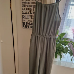 Grön ärmlös jumpsuit H&M cut out - Snygg ljusgrön jumpsuit från H&M med ärmlös design och elastisk midja. Baksidan har en cool cut out-detalj som ger extra edge. Jumpsuit är i ett mjukt, lätt tyg och har en rak, avslappnad passform. Perfekt för varma dagar och chill vibes.