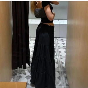 Svart volang långkjol - Supersnygg svart långkjol med flera volanger som ger ett flowy och trendigt intryck. Kjolen har hög midja och är perfekt att styla med crop tops eller stickade tröjor. Enkel men ändå riktigt cool look.