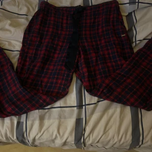 Rödblå rutiga byxor Hampton Republic - Rutiga byxor från Hampton Republic i rött och mörkblått med tunna guldiga linjer. Mjukt bomullstyg och bekväm passform med snörning i midjan. Perfekta för chill dagar hemma eller som pyjamasbyxor.