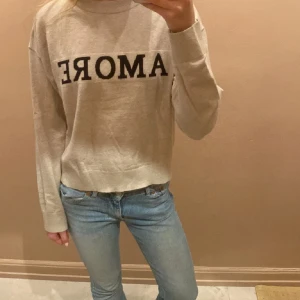 Beige stickad tröja med AMORE-tryck - Säljer denna Amore tröjan från Gina Young. Den är extremt mjuk och skön! Använd en gång så nästan ny skick, den är i storlek 158/164❣️💕