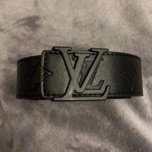 Svart  skärp i skinn - Snyggt svart skärp från  med bred design och ikoniskt -spänne i metall. Skärpet är gjort i skinn och har diskreta monogramdetaljer längs bandet. Perfekt för att lyfta vilken outfit som helst.
