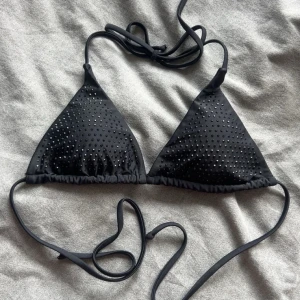 Bikiniöverdel - Snygg svart trekantsbikini med glittriga paljettdetaljer. Klassisk modell med knyt i nacken och ryggen.