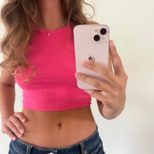 Rosa croppad ribbad linnetopp - Säljer en snygg croppad linnetopp i stark rosa färg. Toppen är ribbad och ärmlös och knappt använd!