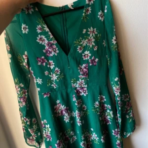 Grön blommig klänning från Nelly - Super fin sommarklänning från Nelly storlek 34, i en härlig grön färg, har en liten defekt (litet hål/lös tråd?) se sista bilden, men syns knappt och inget man tänker på när klänningen är på! 💚