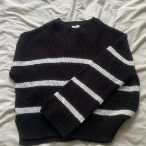 Svartvit randig stickad tröja Kappahl - Säljer en svart stickad tröja från Kappahl med vita horisontella ränder. Tröjan har en klassisk rund halsringning och långa ärmar. Den är ribbstickad och har en lite loose passform, perfekt för lager på lager under höst och vinter.