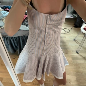Randig kort sommarklänning S - Superfin kort klänning med smala axelband och knappar framtill. Tunt bomullstyg med vita, blå och röda ränder. Utsvängd kjol och figurnära överdel ger en söt och fräsch look, perfekt för varma dagar.