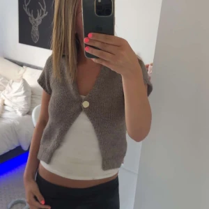 Brun stickad väst från Zara - Kort, brun stickad kofta från Zara med v-ringning och en stor, rund knapp framtill. Koftan har korta ärmar och en loose passform. Tveka inte att höra av dig vid funderingar eller intresse!😁