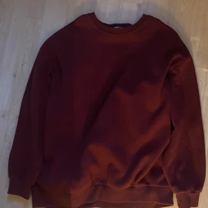 Mörkröd sweatshirt i bomull - Enkel och stilren mörkröd sweatshirt med rund hals och långa ärmar. Tröjan är i mjuk bomull och har ribbade muddar vid ärmslut och nederkant. Perfekt för en chill och avslappnad look.