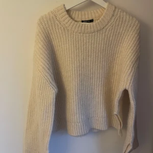 Beige stickad tröja från Gina Tricot - Supermysig beige stickad tröja från Gina Tricot med grov ribbstickning och rund hals. Perfekt för lager-på-lager och chill dagar. Långärmad och lite oversized fit som ger en avslappnad vibe.