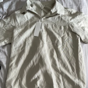 Kortarmad linne half-zip - Kortarmad half-zip linne tröja från Arket i storlek m (48). Aldrig använd. Nypris 790 kr. Perfekt nu till sommaren