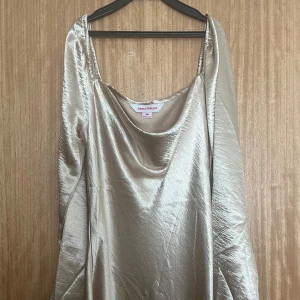 Champagnefärgad siden klänning - Siden långklänning/midi i champagnefärg köp på Asos. Klänningen är aldrig använd. Har ett mjukt, glansigt material som ger en lyxig känsla och elegant look. På bild nr 2 kan man se att den har en liten defekt men syns knappt 