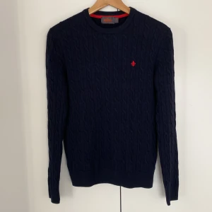 Mörkblå kabelstickad merino tröja från Morris - Säljer denna mörkblåa kabelstickade morris tröjan i 100% merino. Storlek small. Den är i bra skicka och är en 9/10 och har inga fläckar eller hål på sig. Passar perfekt till hösten och är riktigt snygg. Jag är 169 cm lång och den är sitter lite tajt. Jag hade rekommenderat att vara runt 160 cm för att den ska ha bättre passform. Hör av dig vid mer frågor eller funderingar!