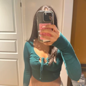 Mörkgrön croppad knyt-topp - Snygg mörkgrön croppad topp med långa ärmar och knyt framtill. Toppen är ribbad och är från new Yorker. Den har aldrig använts. Den är i storlek M men är mer som en S