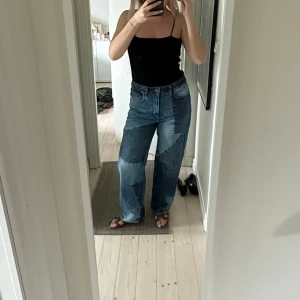 Patchwork wide jeans i blå denim - Säljer ett par blå patchwork jeans med bred passform och hög midja. Jeansen har flera olika denimnyanser i coola geometriska mönster och raka ben. Perfekta för dig som vill sticka ut med en unik streetstyle-look.
