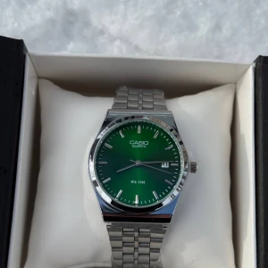 Casio klocka med grön urtavla - Stilren Casio klocka med grön urtavla och klassisk silverfärgad länk i metall. Urtavlan har tydliga index, datumvisning och en snygg minimalistisk look. Perfekt accessoar för dig som gillar enkel men modern design.🔥💚🍏