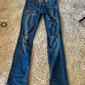 Blå slitna bootcut jeans från Replay - Säljer ett par blå bootcut jeans från only med slitna detaljer och hål på benen. Jeansen har klassisk femficksdesign, låg midja och är gjorda i jeansmaterial. Perfekta för dig som gillar en edgy och avslappnad stil. Köpte dom här på Plick för 1000 säljer för 600. Åker 14 juni till 23 så köp nu om ni vill ha dom fort❤️