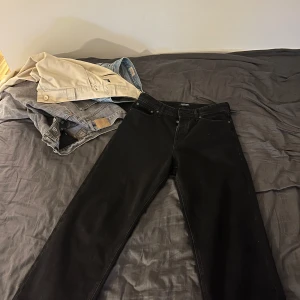 Jack & Jones - Baggy Alex - Säljer ett par svarta jeansbyxor med klassisk femficksdesign och raka ben. Byxorna har normal passform och är tillverkade i ett jeanstyg. Perfekta för dig som gillar en enkel och stilren look.