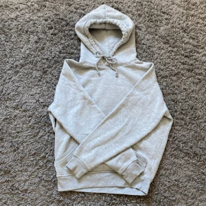Ljusgrå hoodie  - Säljer en enkel och stilren ljusgrå hoodie med huva och dragsko. Tröjan har en stor magficka och ribbade muddar vid ärmslut och nederkant. Perfekt för en avslappnad look, perfekt för sommarkvällarna!💓