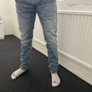 Replay anbass jeans  - Säljer ett par ljusblå jeans från Replay med klassisk femficksdesign och snygga sömmar på bakfickorna. Jeansen har en normal passform och är perfekta för en avslappnad stil. Midjan är midwaist och de är tillverkade i ett bekvämt denimtyg. Storlek är 34/34