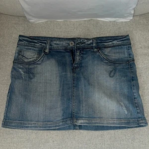Blå jeanskjol med fickor - Säljer en klassisk blå jeanskjol med snygga slitningar och dekorativa sömmar på fickorna. Kjolen har två framfickor, två bakfickor och hällor för skärp. Perfekt för dig som gillar en tidlös denimlook. Aldrig använd bara testat. Fråga för mått😁
