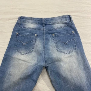 Ljusblå jeans med bootcut - Snygga ljusblå jeans med bootcut och klassisk femficksdesign. De har en lågmidjad passform och är perfekta för en avslappnad stil. Jeansen har en lätt tvättad look som ger en cool vintagekänsla.