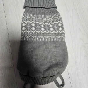 Grå stickad hundtröja från Dogman - Säljer en grå stickad hundtröja från Dogman med vitt nordiskt mönster. Tröjan är mjuk och har hål för frambenen samt resår vid hals och nederkant. Perfekt för kyliga dagar och mysiga promenader.
