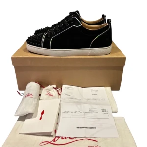 Christian Louboutin - Säljer ett par svarta sneakers från Christian Louboutin med rund tå och platt vit sula. Skorna har svarta nitar på tån och är tillverkade i mocka med svarta skosnören. Snygga kontrastsömmar och exklusiv känsla. Lägg pris förslag 