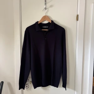 Stickad tröja - Säljer en stilren mörkblå piké långärmad tröja från dressman i merinoull. Storlek L, Inga defekter, bra skick, vid frågor och funderingar är det bara att höra av sig:)