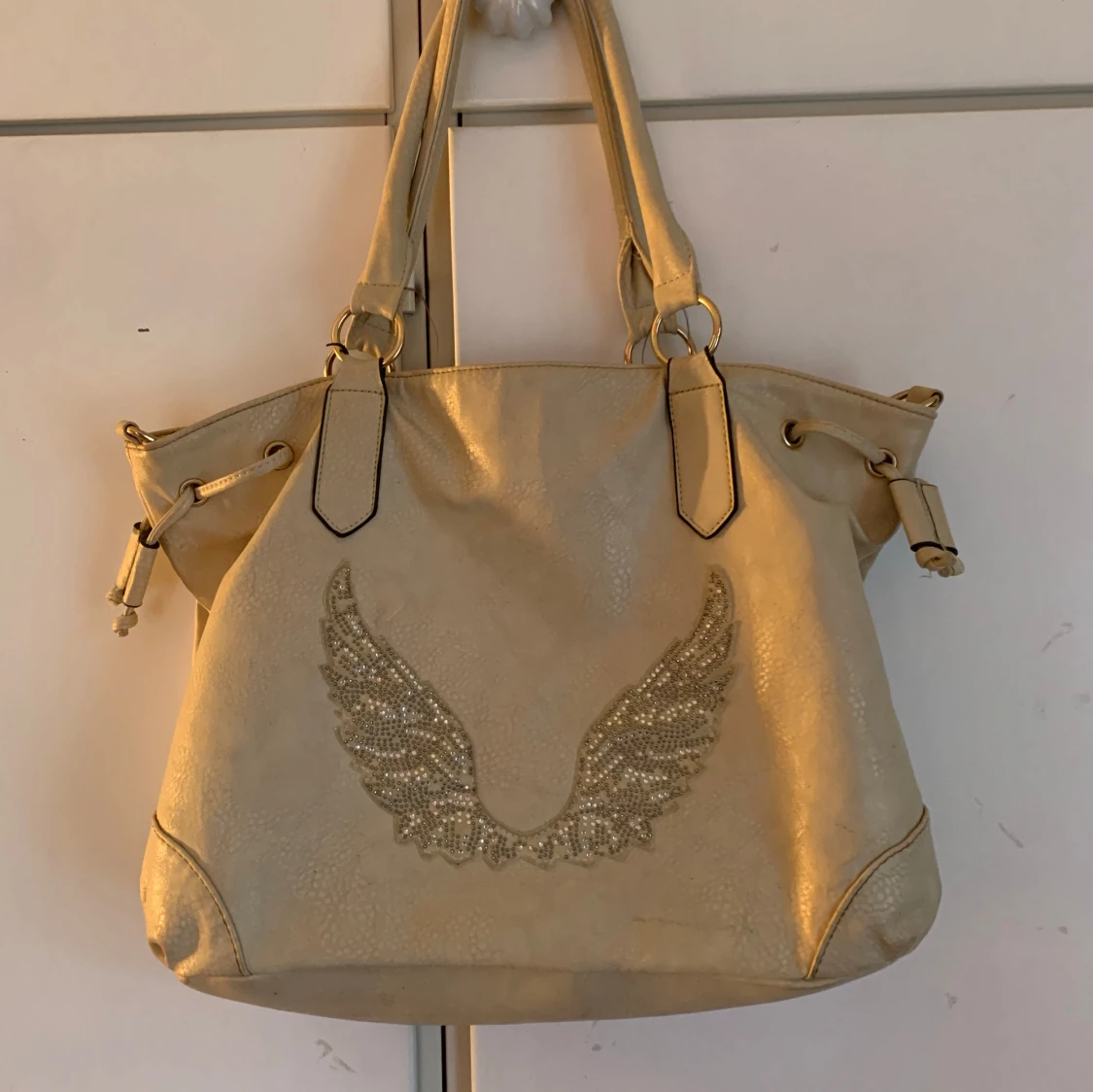 Beige axelvĂ€ska med vingarđ