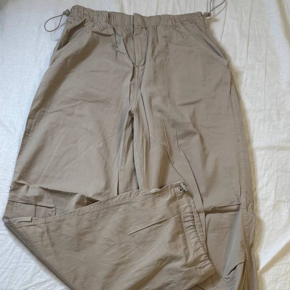 Säljer ett par beige cargopants från Pull&Bear med dragsko i midjan och dragkedja. Byxorna har flera fickor och är perfekta för en avslappnad stil. Materialet känns lätt och bekvämt. Pris kan diskuteras. Farkut & Housut.